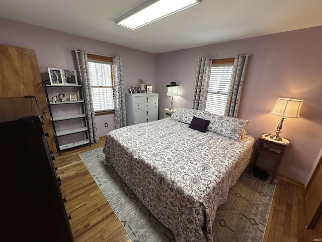 bedroom with multiple windows, baseboards, and dark wood finished floors