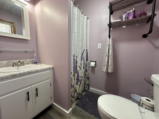 full bath featuring wood finished floors, vanity, toilet, and baseboards