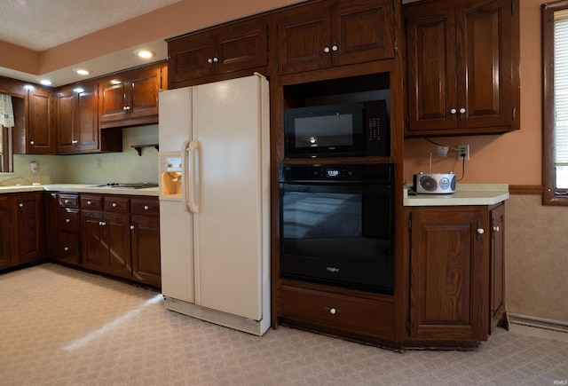 kitchen with a sink, black appliances, light countertops, and dark brown cabinetry