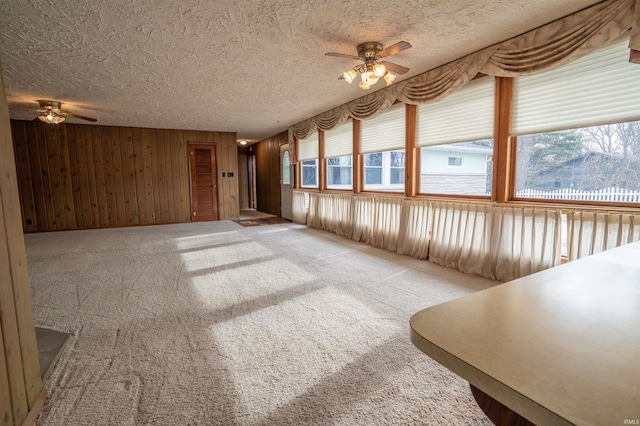 unfurnished living room with light carpet, ceiling fan, and a textured ceiling