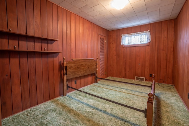 bedroom featuring carpet floors, visible vents, and wooden walls