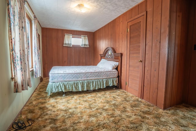 carpeted bedroom featuring wood walls