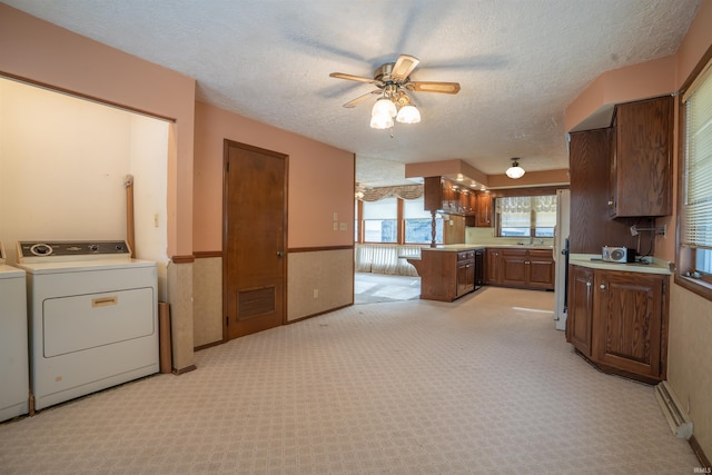 kitchen with light countertops, visible vents, light carpet, washer / dryer, and a peninsula