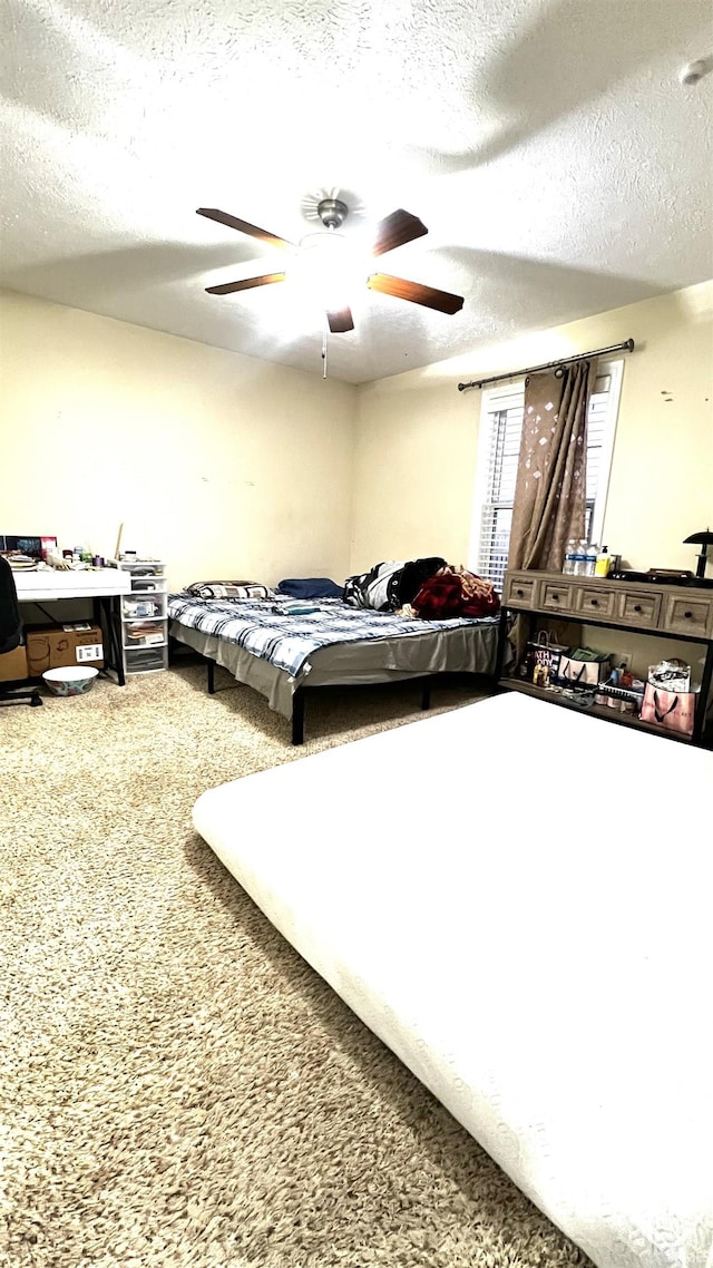 carpeted bedroom featuring a ceiling fan and a textured ceiling