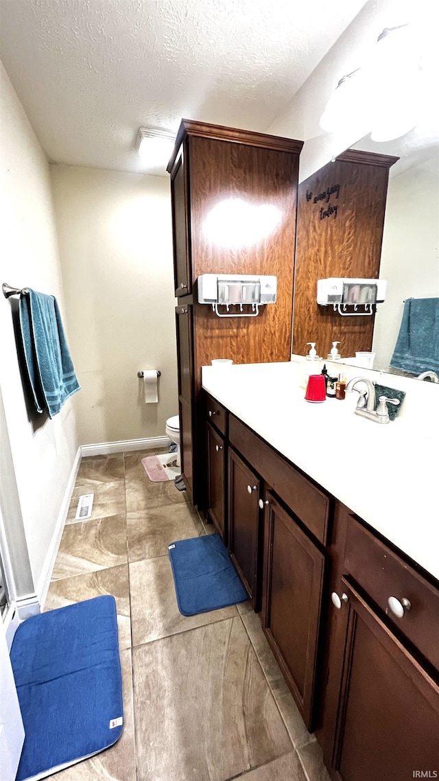 full bathroom featuring baseboards, toilet, a textured ceiling, and vanity