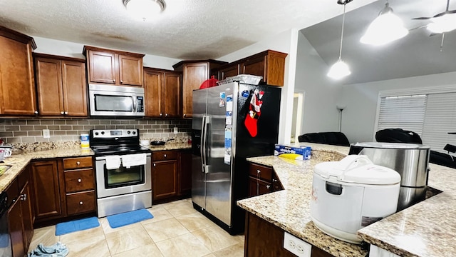 kitchen with open floor plan, stainless steel appliances, hanging light fixtures, and tasteful backsplash