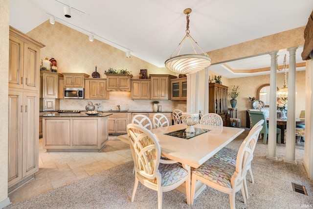 dining space featuring stone tile floors, visible vents, rail lighting, ornate columns, and high vaulted ceiling