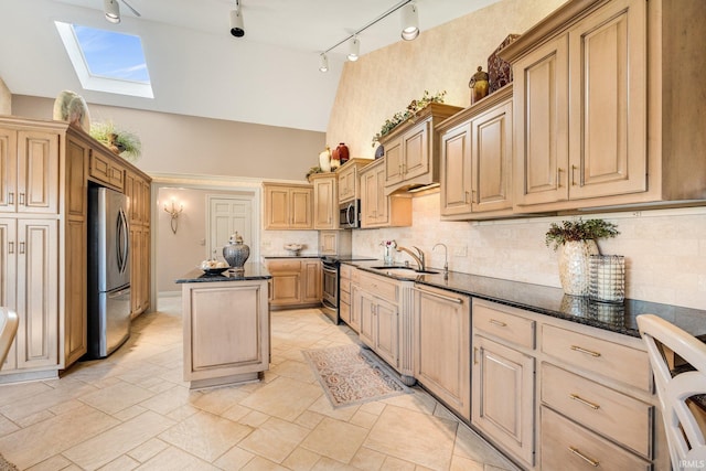 kitchen featuring a skylight, dark stone counters, a kitchen island, stainless steel appliances, and light brown cabinetry