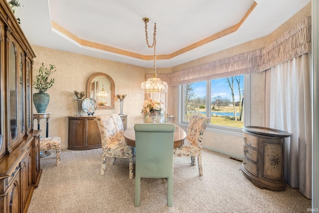 dining area with a tray ceiling, light colored carpet, and baseboards