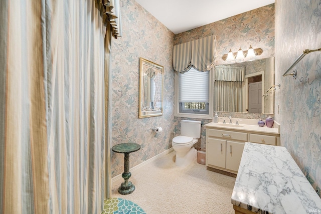 bathroom featuring baseboards, vanity, toilet, and wallpapered walls