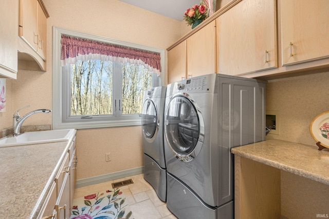 clothes washing area with washing machine and dryer, a sink, visible vents, baseboards, and cabinet space