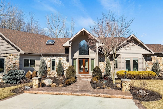 mid-century modern home with stone siding, french doors, and a shingled roof