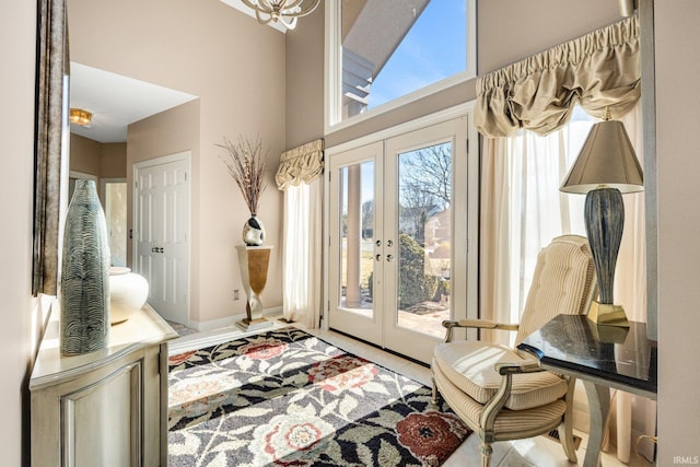 doorway to outside with french doors, a towering ceiling, and an inviting chandelier