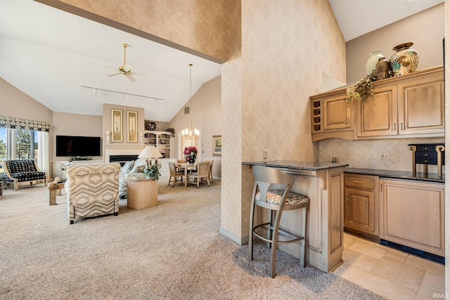 kitchen with dark countertops, a fireplace, high vaulted ceiling, and open floor plan