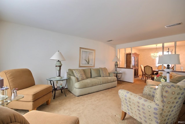 living area with visible vents, light carpet, and an inviting chandelier