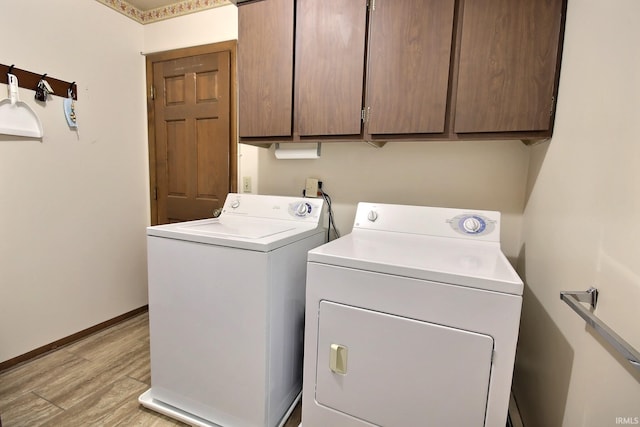 laundry room featuring baseboards, washing machine and clothes dryer, cabinet space, and light wood-style floors