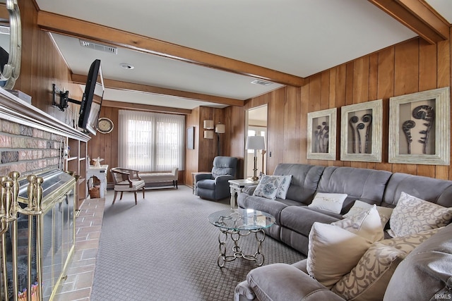 living room with wood walls, carpet flooring, visible vents, a brick fireplace, and beamed ceiling