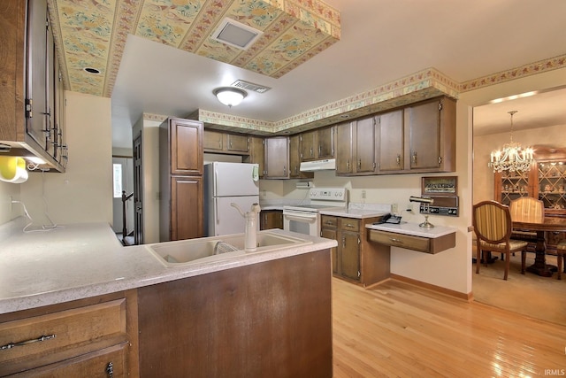 kitchen with under cabinet range hood, white appliances, a sink, visible vents, and light countertops