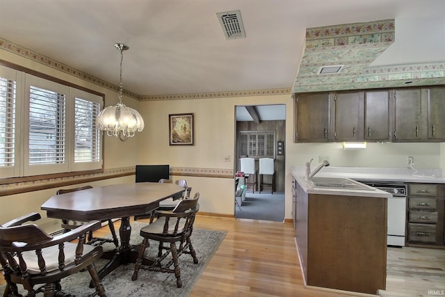 dining space with light wood-style flooring, visible vents, and baseboards