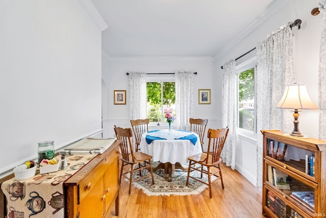 dining room featuring a healthy amount of sunlight, light wood finished floors, and ornamental molding