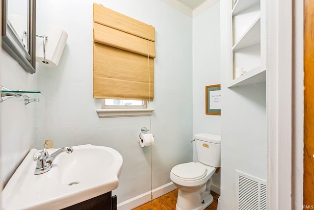 bathroom with baseboards, visible vents, toilet, wood finished floors, and vanity