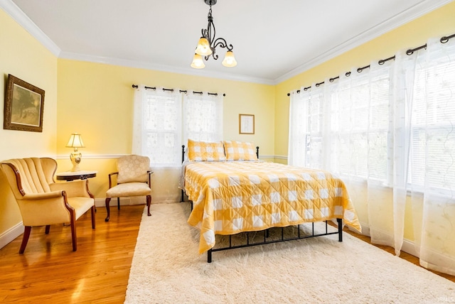 bedroom with baseboards, multiple windows, wood finished floors, and crown molding