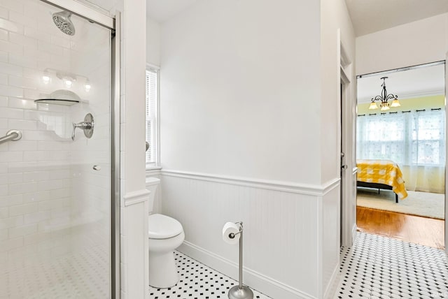 bathroom featuring toilet, an inviting chandelier, wainscoting, connected bathroom, and a shower stall