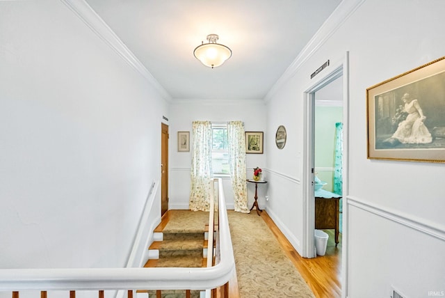 corridor featuring light wood-style floors, baseboards, and ornamental molding