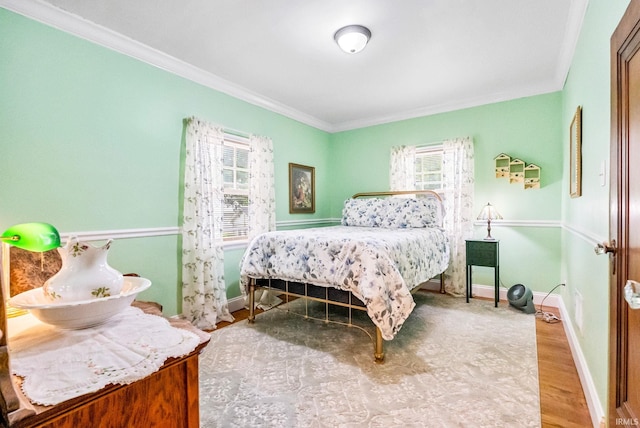 bedroom with baseboards, ornamental molding, and wood finished floors