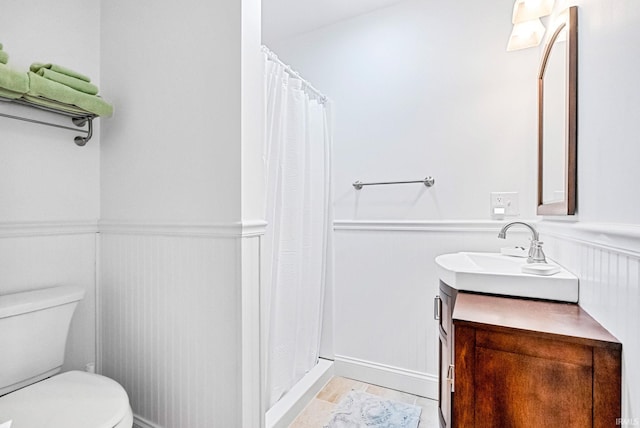 full bath with curtained shower, wainscoting, vanity, and toilet