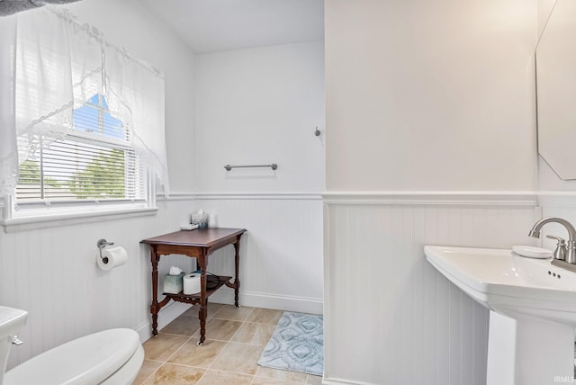 bathroom featuring tile patterned flooring, wainscoting, a sink, and toilet