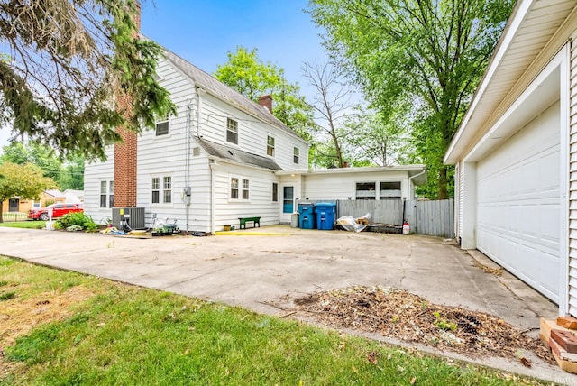 view of home's exterior with central AC unit, a garage, driveway, roof with shingles, and a chimney