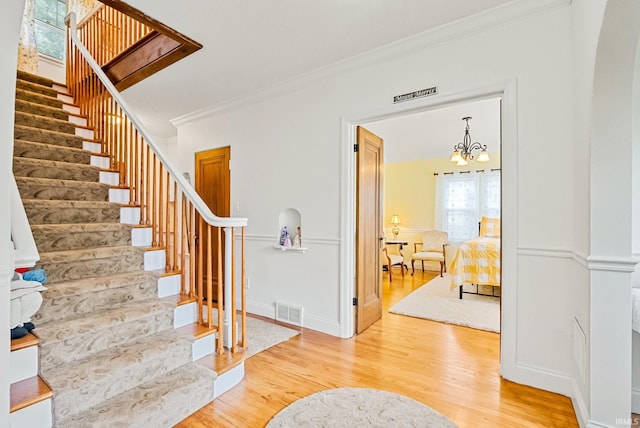 foyer featuring stairs, visible vents, wood finished floors, and ornamental molding