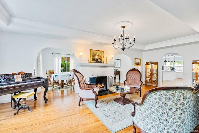 sitting room with a fireplace, a chandelier, a raised ceiling, and wood finished floors