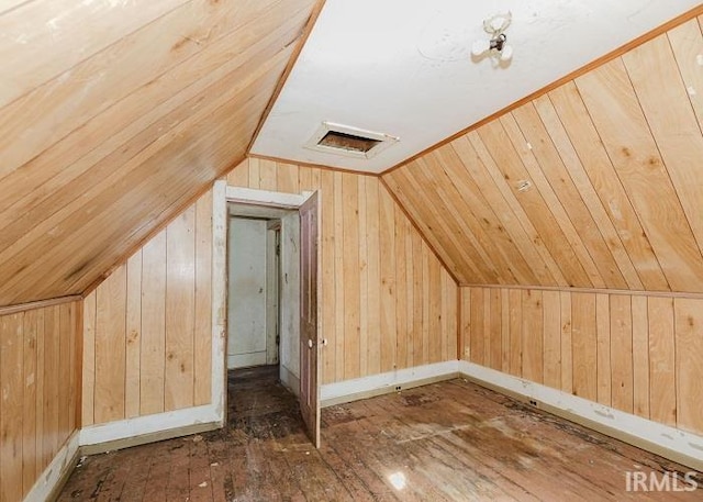 bonus room featuring lofted ceiling, wooden walls, visible vents, and dark wood-type flooring