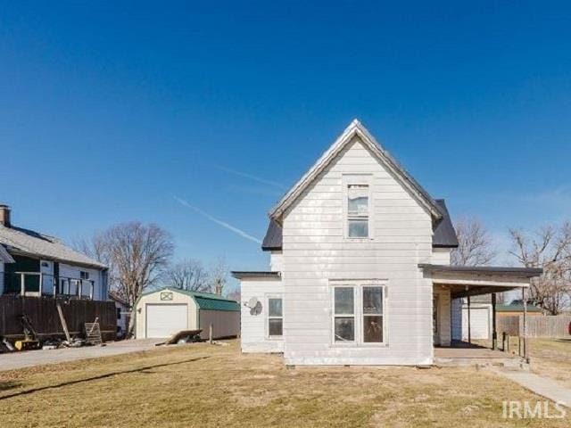 rear view of property featuring a yard, an outdoor structure, and a detached garage