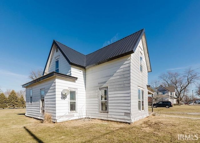 back of house with metal roof and a yard