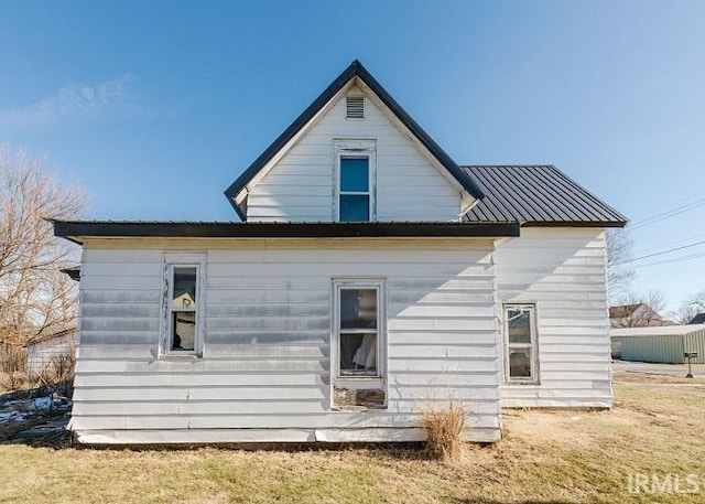 back of property with metal roof and a yard