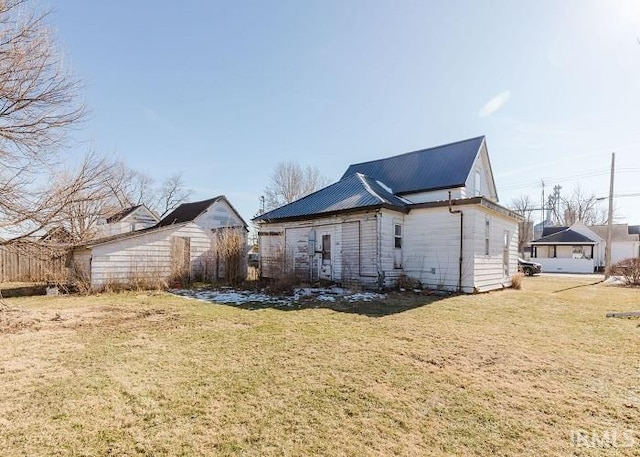 view of side of home with metal roof and a lawn