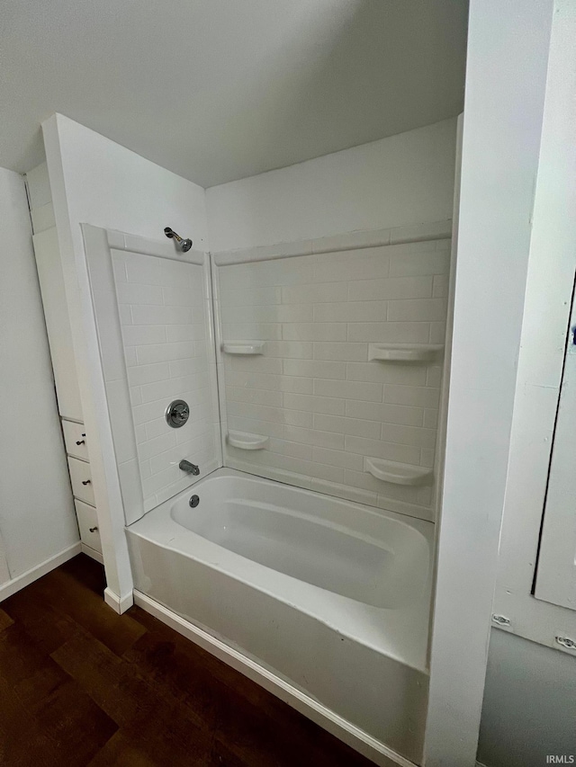 bathroom featuring washtub / shower combination, baseboards, and wood finished floors