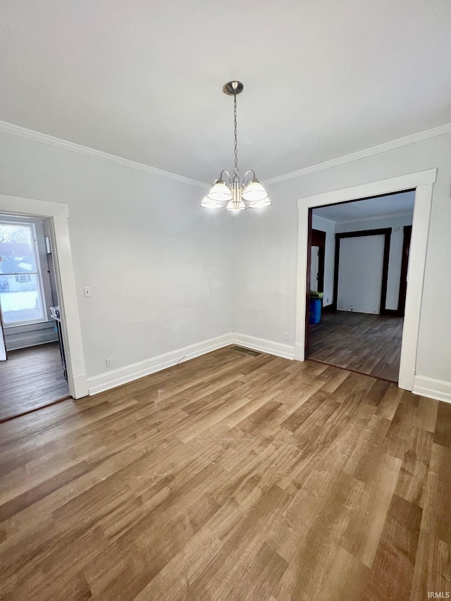 unfurnished dining area with crown molding, baseboards, wood finished floors, and a notable chandelier