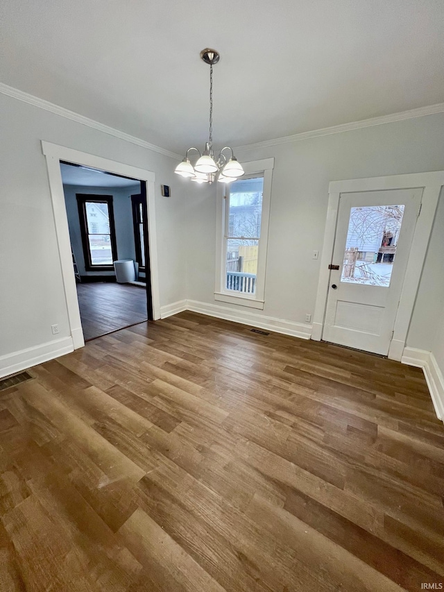 unfurnished dining area with ornamental molding, baseboards, an inviting chandelier, and wood finished floors