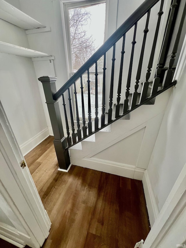 staircase with wood finished floors, a wealth of natural light, and baseboards