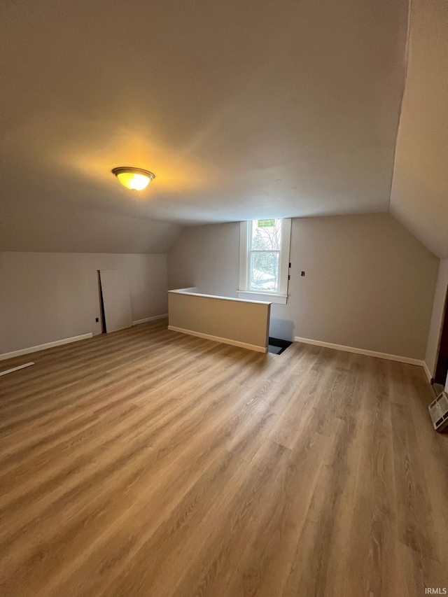 bonus room with vaulted ceiling, baseboards, and wood finished floors