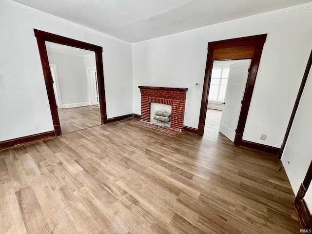 unfurnished living room with ornamental molding, light wood-type flooring, a fireplace, and baseboards