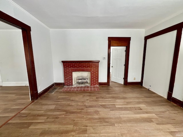 unfurnished living room with baseboards, a fireplace, ornamental molding, and wood finished floors