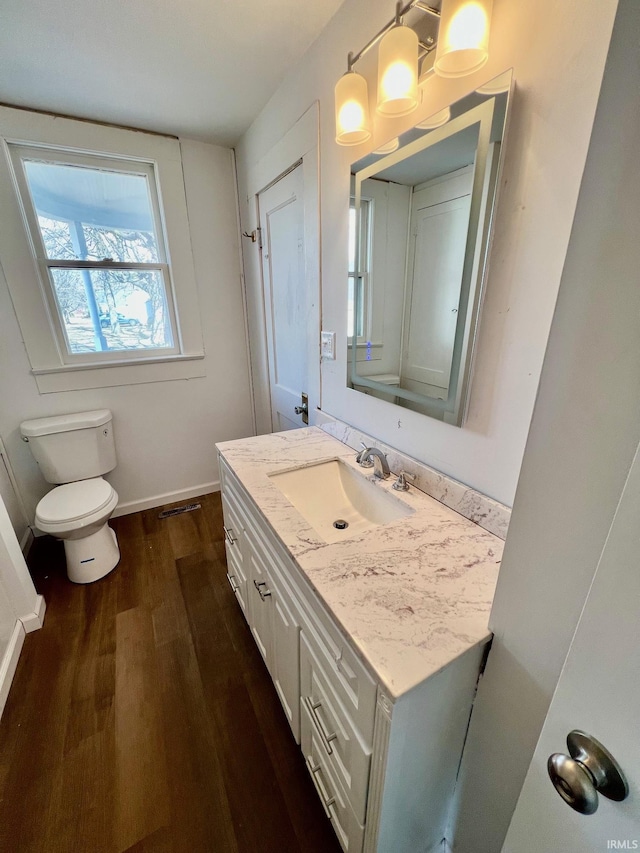 bathroom featuring toilet, wood finished floors, visible vents, vanity, and baseboards