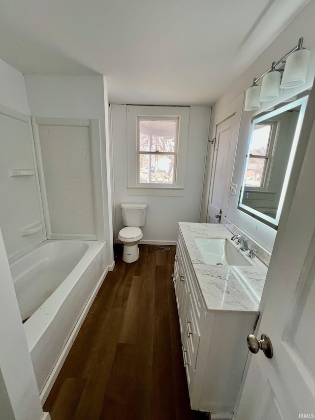 full bath featuring toilet, a wealth of natural light, wood finished floors, and vanity