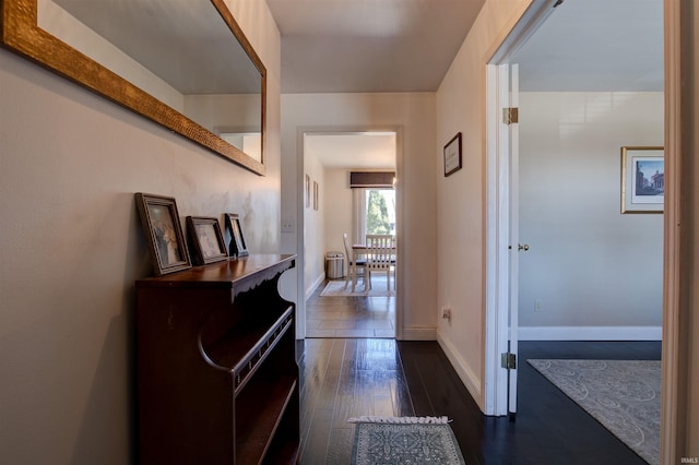 corridor with dark wood-style floors and baseboards