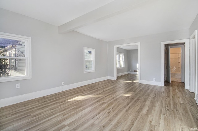 interior space with light wood-style floors, beam ceiling, and baseboards